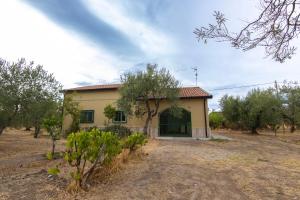 a small yellow house in a field with trees at BAsicNature in Lavello