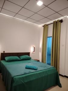 a bedroom with a large bed with green sheets at Yesumishi Airport Villas - Transit Hotel Katunayake in Seeduwa