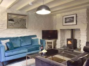 a living room with a blue couch and a fireplace at Cosy, characterful cottage in Betws-y-Coed in Betws-y-coed