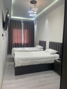 a bedroom with two beds and a television in it at Квартира в центре города in Dushanbe