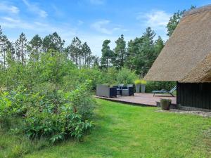 ein Garten mit einer Holzterrasse mit Strohdach in der Unterkunft Holiday Home Awenasa - 4-1km from the sea by Interhome in Nørre Nebel