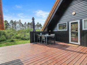 eine Holzterrasse mit einem Tisch und Stühlen auf einem Haus in der Unterkunft Holiday Home Awenasa - 4-1km from the sea by Interhome in Nørre Nebel