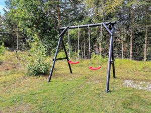 eine leere Schaukel mit zwei roten Schaukeln in der Unterkunft Holiday Home Awenasa - 4-1km from the sea by Interhome in Nørre Nebel + 21 Fotos