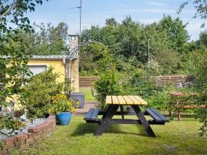 a picnic table and benches in a garden at Holiday Home Aslak - 600m from the sea by Interhome in Glesborg