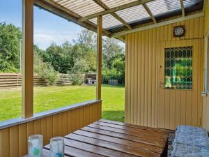 a screened porch with a wooden table and a clock at Holiday Home Aslak - 600m from the sea by Interhome in Glesborg +18 photos
