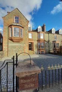 a large brick house with a sign in front of it at Kirkcudbright Holiday Apartments - Apartment B in Kirkcudbright