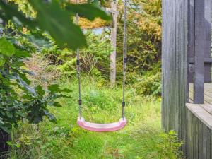 a red swing hanging from a wooden fence at Holiday Home Isabel - 500m from the sea by Interhome in Torsted