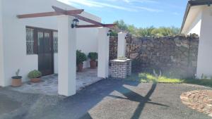 una casa blanca con un muro de piedra y un patio en Mooi Nooi, en Beaufort West