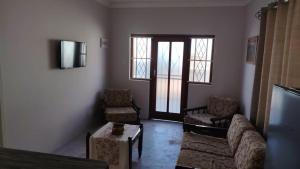 Una sala de estar con un sofá y sillas y un televisor. en Mooi Nooi, en Beaufort West