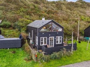 a small black house on a grass field at Holiday Home Benni - 75m to the inlet by Interhome in Løgstør