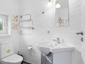 a white bathroom with a sink and a toilet at Holiday Home Thrugels - 600m from the sea by Interhome in Hadsund +14 photos