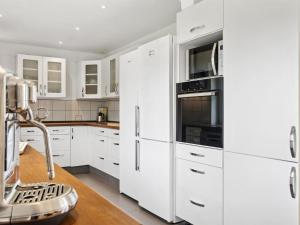 eine weiße Küche mit weißen Schränken und Geräten in der Unterkunft Holiday Home Ronia - 900m from the sea by Interhome in Bøtø By