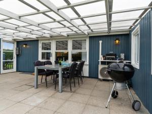 a patio with a table and chairs and a grill at Holiday Home Kjera - 450m from the sea by Interhome in Hadsund