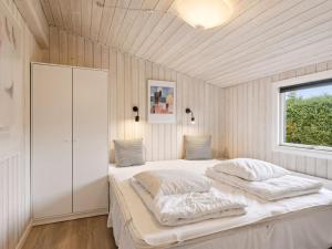 a bedroom with a bed with white sheets and a window at Holiday Home Kjera - 450m from the sea by Interhome in Hadsund +10 photos
