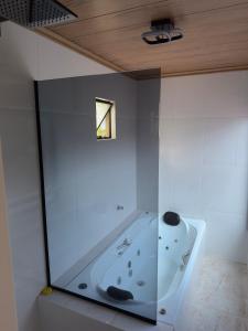 a glass walled tub in a bathroom with a window at Chalé Vale da Paz 500m da Praca in Palmeiras