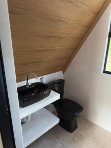 a bathroom with a black toilet and a sink at Chalé Vale da Paz 500m da Praca in Palmeiras