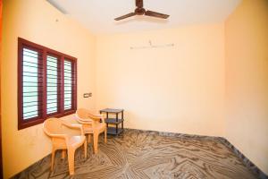 a room with two chairs and a table and a ceiling fan at White Pearl Homes in Kuttālam +17 photos