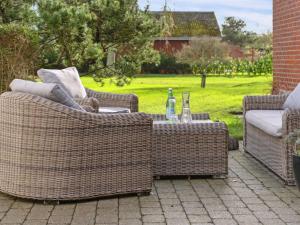 HadsundにあるHoliday Home Bertold - 100m from the sea by Interhomeの3脚の籐椅子とボトルが置かれたテーブル