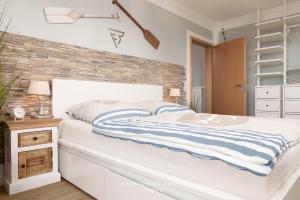 Un dormitorio con una cama blanca y una pared de ladrillo. en FeWo AquaMarin, en Stein