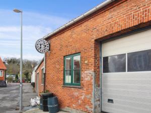 a brick building with a garage door and a clock at Holiday Home Elvira - 300m from the sea by Interhome in Svaneke