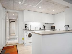 a kitchen with white cabinets and a washer at Holiday Home Ilsebet - 150m from the sea by Interhome in Børkop