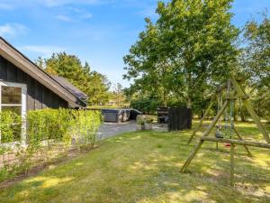 un patio con columpios en el césped en Holiday Home Roska - 1-3km from the sea by Interhome, en Saltum