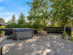 un patio con bañera de hidromasaje y banco en Holiday Home Roska - 1-3km from the sea by Interhome, en Saltum