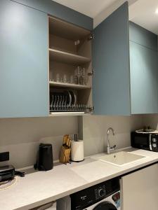 una cucina con mobili blu e un lavandino di 7th floor Studio a Xánthi Altre 4 foto