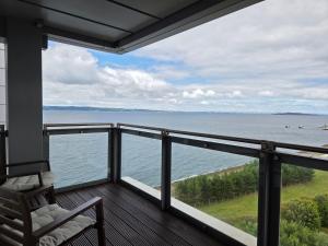 d'un balcon avec une chaise et une vue sur l'eau. dans l'établissement Edinburgh City Sea View Harbour Apartment, à Édimbourg