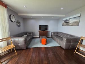 - un salon avec un canapé en cuir et une télévision à écran plat dans l'établissement Edinburgh City Sea View Harbour Apartment, à Édimbourg