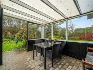 a conservatory with a table and chairs on a patio at Holiday Home Ensio - 300m to the fjord by Interhome in Vinderup