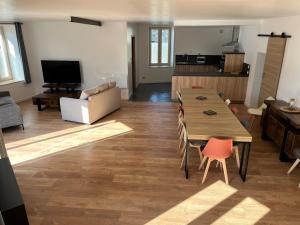 a living room with a table and chairs and a television at Hébergement La Fontaine in La Coudre