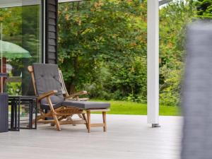 a wooden rocking chair sitting on a porch at Holiday Home Anett - 375m from the sea by Interhome in Fårevejle +23 photos