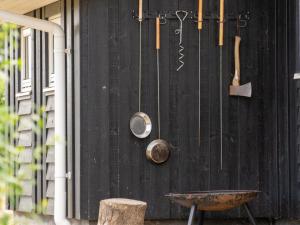 a black wall with pots and pans and a wheelbarrow at Holiday Home Sira - 350m from the sea by Interhome in Spodsbjerg