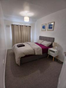a bedroom with a large bed with a purple blanket at Rose Cottage-4 BED HOUSE FOR CONTRACTORS & FAMILIES Close to M6, J10-NO PARTIES ALLOWED in Walsall