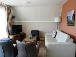 a living room with a couch and chairs and a tv at Holiday Home Ruiten AA comfort by Interhome in Vlagtwedde