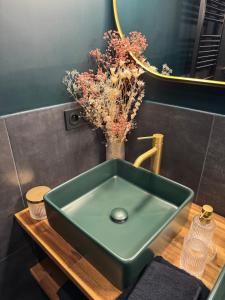 a green sink in a bathroom with a vase of flowers at SV- Le Secret Marseillais Love room in Marseille