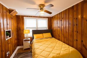 a bedroom with wooden walls and a bed with a ceiling fan at Florence in Milford