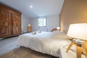 Un dormitorio con una gran cama blanca y una lámpara. en L'envolée Sauvage, en Saint-Nectaire