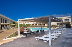 a pavilion with tables and chairs next to a pool at Apartamentos Charco del Conde in Valle Gran Rey
