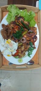 a plate of food with meat and vegetables on a table at Ko Lake Room in Ahangama
