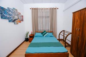 マータラにあるIdeal Residenceのベッドルーム1室(青いベッド1台、木製キャビネット付)