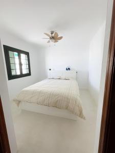 a white bedroom with a bed and a ceiling fan at Casa Rofe in Playa Honda