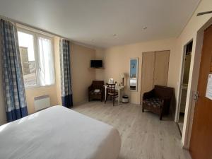 a hotel room with a bed and a table and chairs at Logis Hôtel & Restaurant - Le Bretagne in Sillé-le-Guillaume
