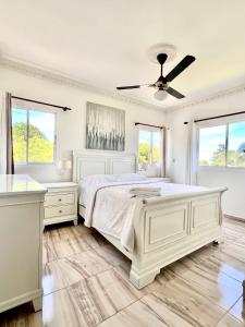 a white bedroom with a bed and a ceiling fan at Beautiful and confortable apt in Puerto Plata