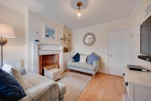 ein Wohnzimmer mit Couch und Kamin in der Unterkunft Twitten Cottage in Southwold