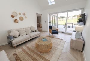 a living room with a couch and a table at Tai Porth Llechog Bungalow By Birch Stays in Amlwch