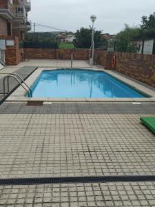 a swimming pool with a tile floor and a brick wall at Apartamento Casuca, terraza y jardín in Ajo
