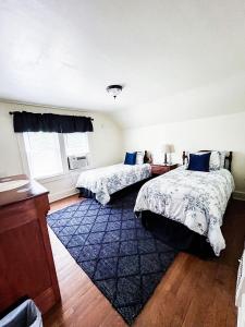 a bedroom with two beds and a blue rug at Walk to Golfcourse EnJoie House PetFriendly in Endicott