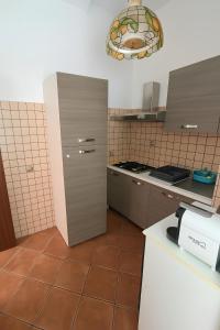 a kitchen with a refrigerator and a tile floor at La casa del Villaggio in Torre Faro +5 photos